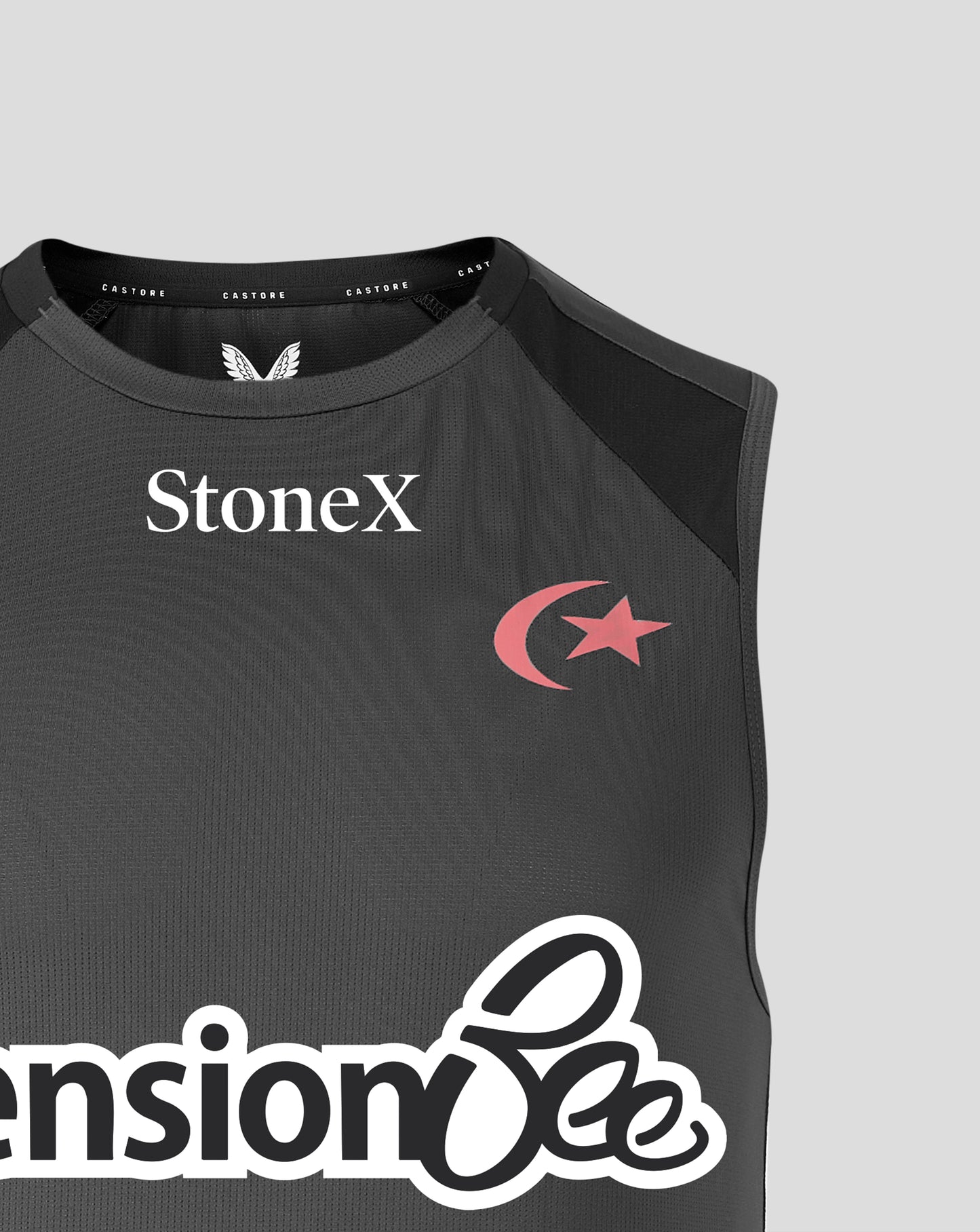 Close-up of a sleeveless dark gray athletic top with black shoulder panels, featuring the StoneX logo in white on the chest and a pink crescent and star graphic. The bottom shows part of a large white script logo.