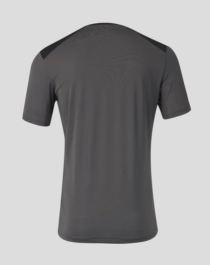 A dark gray athletic t-shirt shown from the back, featuring subtle wavy texture and contrasting dark shoulder panels, set against a solid light gray background.