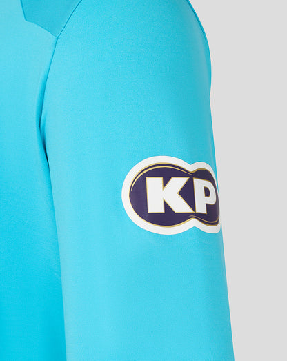 Close-up of a blue shirt with a KP logo on the sleeve against a white background