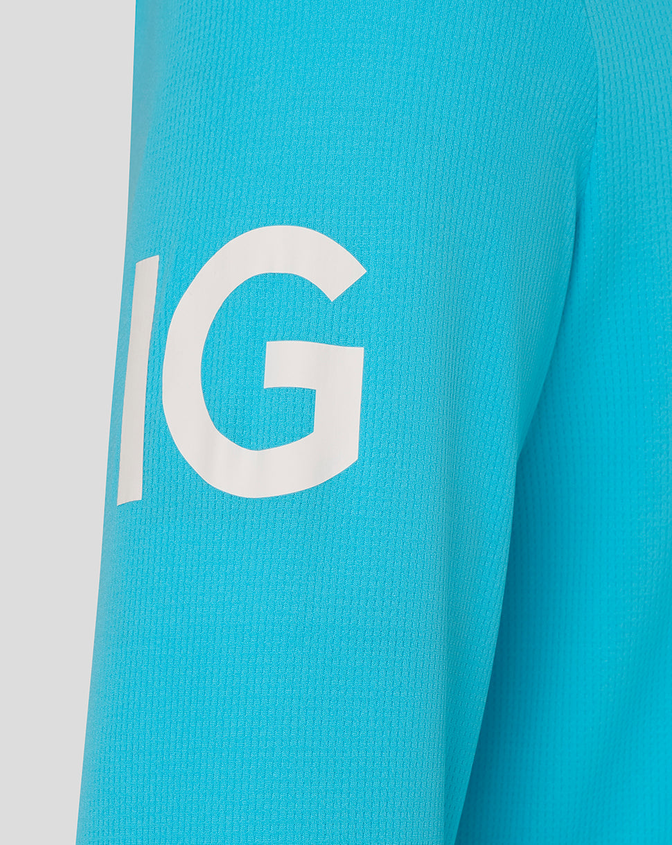 Close-up of a turquoise sleeve with a large white letter 'G' on a light gray background