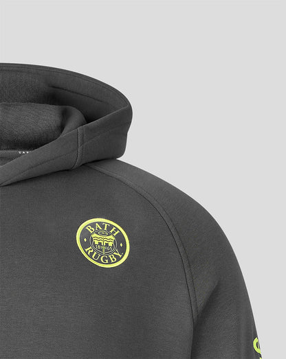 Close-up of a dark gray heathered hoodie featuring a circular yellow and black 'BATH RUGBY' crest patch on the chest, set against a solid light gray background.