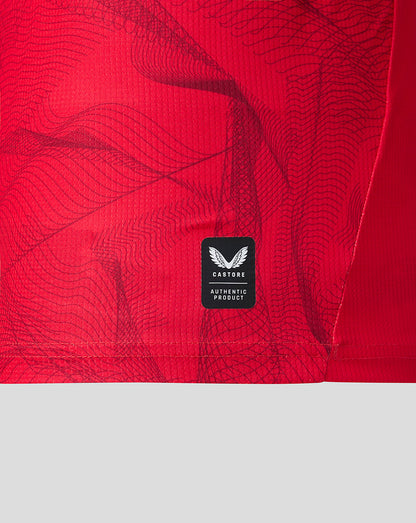 Close-up of a bright red athletic garment with a subtle wavy pattern and a black Castore Authentic Product label near the lower center.