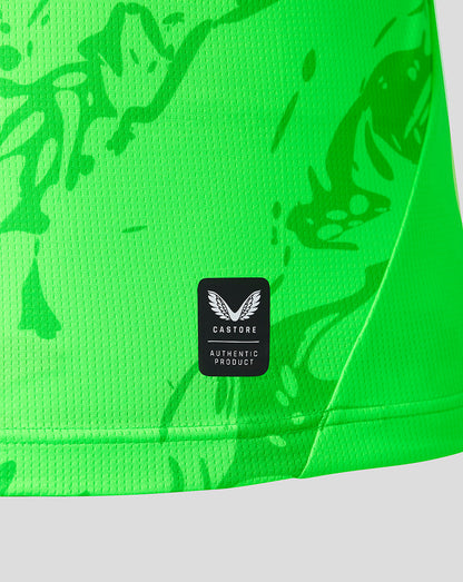 Close-up of a bright neon green athletic garment with a tonal abstract pattern and a black Castore brand patch on the front.