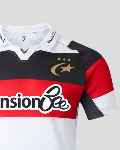 A close-up of a short-sleeve rugby jersey with a black, red, and white horizontal color-blocked design. The jersey features a gold crescent and star logo with three stars on the chest, and a large 'Pension Bee' sponsor logo across the red band.