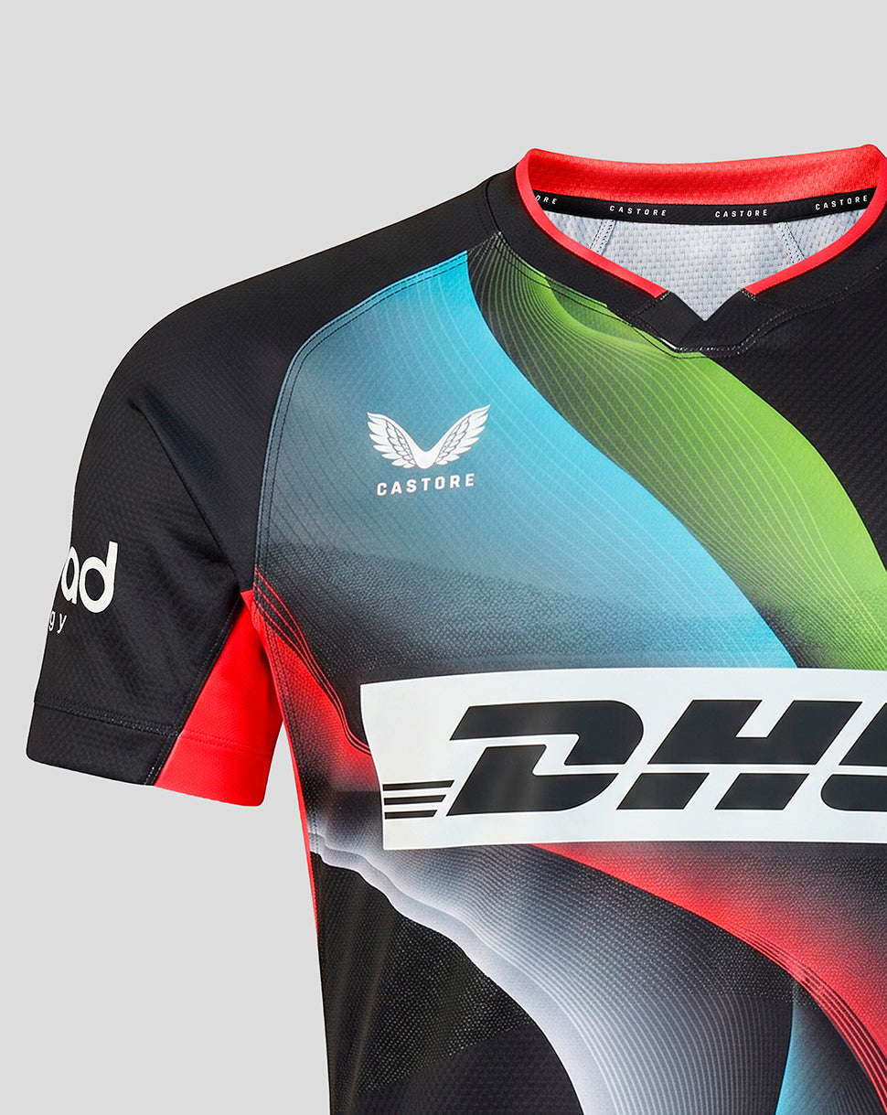A close-up of a short-sleeve athletic cycling jersey with a black base and vibrant abstract graphic panels in blue, green, and red. The jersey features the Castore wing logo on the chest and a large white DHL sponsor logo across the front.