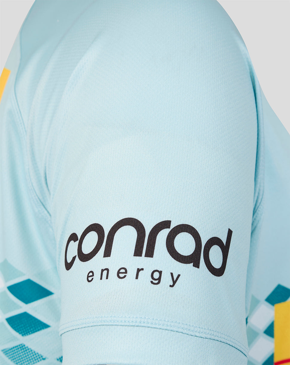 Close-up of a light blue athletic jersey sleeve with the black 'conrad energy' logo printed on the back, showing part of a geometric pattern in teal and yellow.