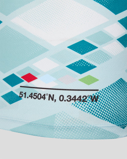 Close-up of a light blue and white geometric patterned fabric with teal diamond shapes, a small red accent, and black printed coordinates.