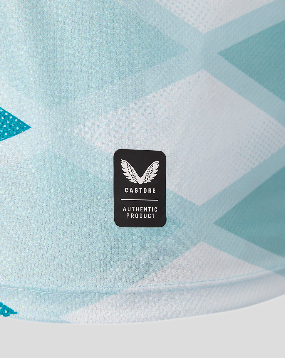 Close-up of a light blue and white geometric patterned fabric with a black Castore brand patch in the center.