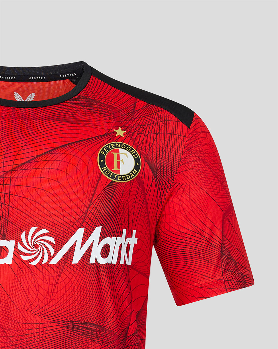 Chest view of Feyenoord home shirt showing crest on left chest and Castore logo on right on red patterned fabric.