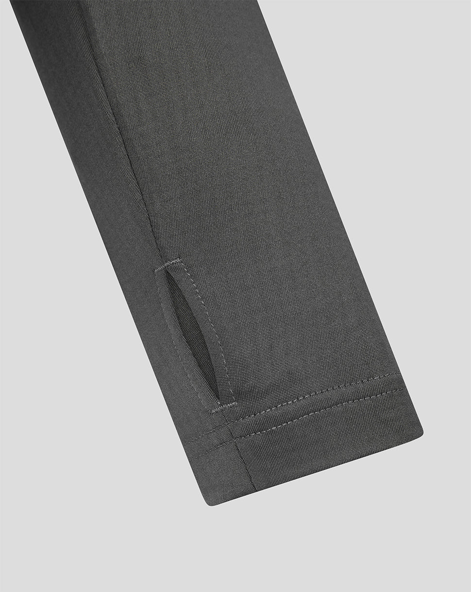 Close-up of a dark gray fabric garment sleeve or pant leg showing a cuff with a stitched loop detail, on a light gray background.