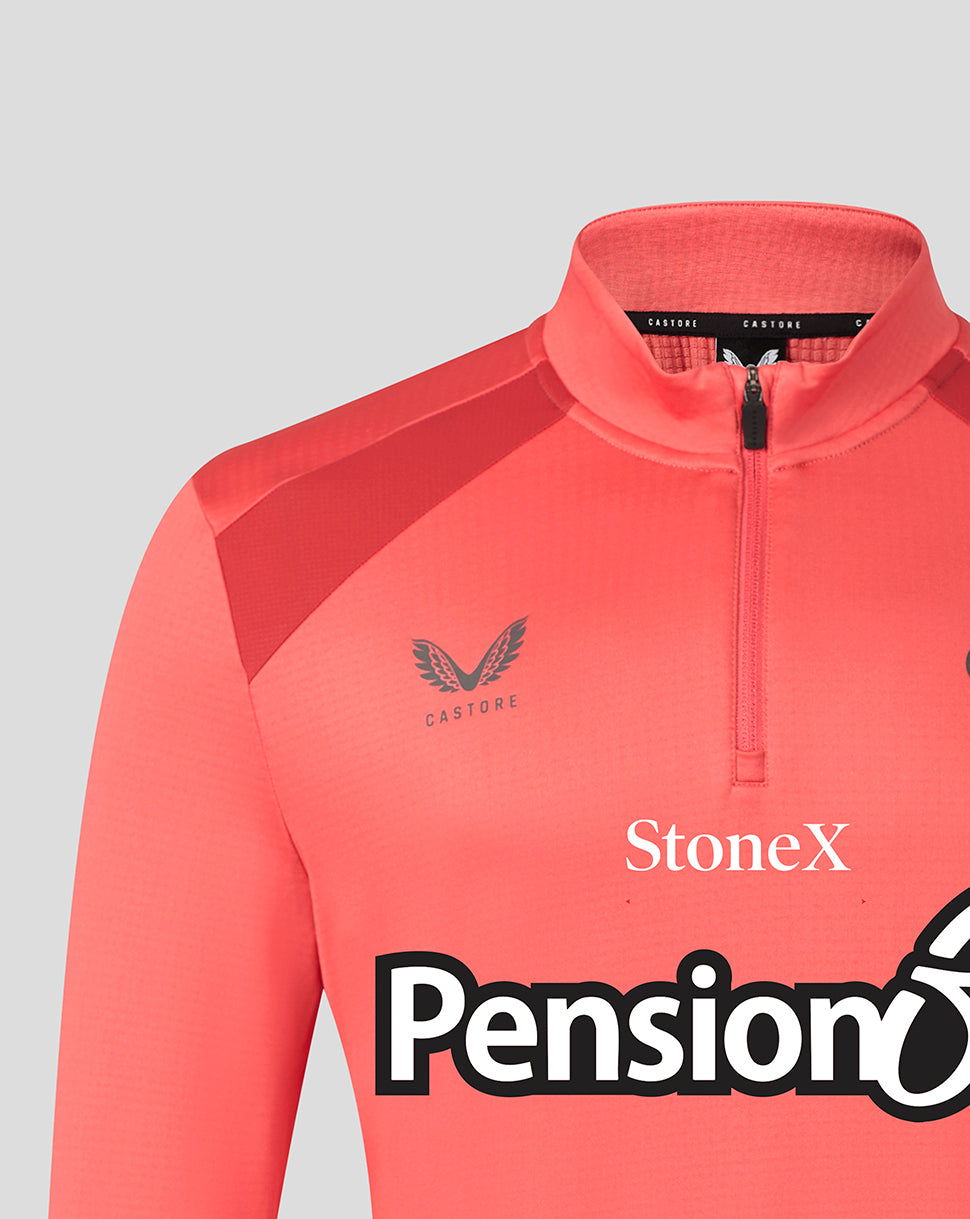 A close-up of a coral pink athletic quarter-zip jacket with a mock neck collar, featuring the Castore wing logo on the chest and sponsor logos StoneX and Pension6.