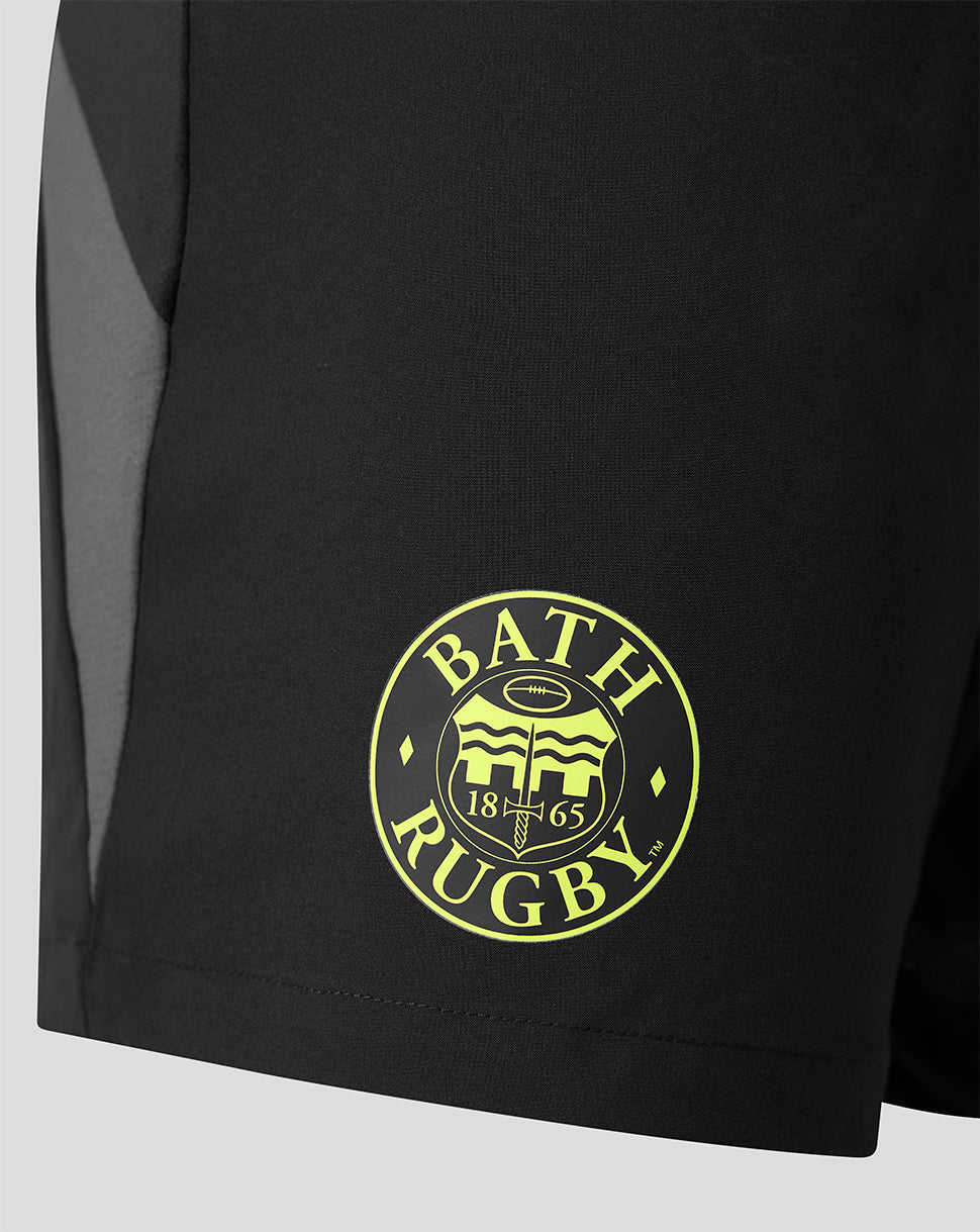 Close-up of a black athletic shorts leg featuring a circular yellow 'BATH RUGBY' crest printed on the lower front and a gray side panel.