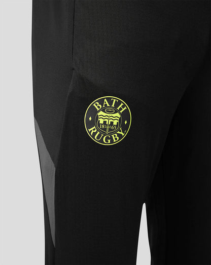 Close-up of black athletic pants with a circular yellow-green Bath Rugby crest patch on the thigh.