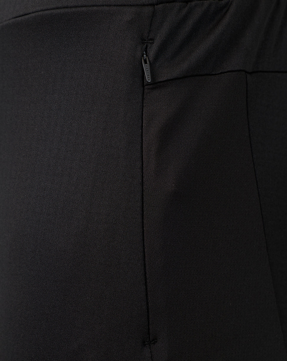 Close-up of black fabric with a vertical seam and a small dark zipper pull, showing the texture and construction detail.
