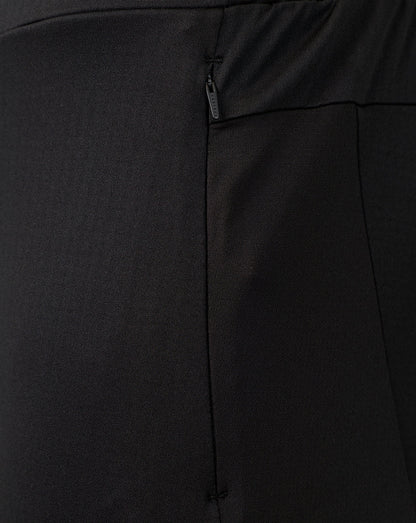 Close-up of black fabric with a vertical seam and a small dark zipper pull, showing the texture and construction detail.