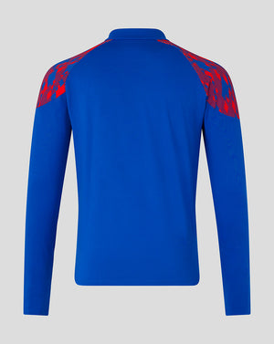 A royal blue long-sleeve athletic top shown from the back, featuring red patterned shoulder panels, on a light gray background.