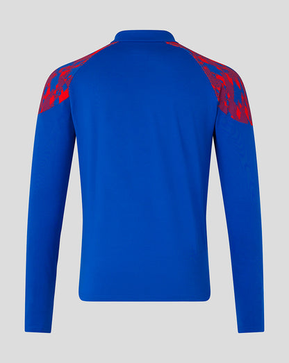 A royal blue long-sleeve athletic top shown from the back, featuring red patterned shoulder panels, on a light gray background.