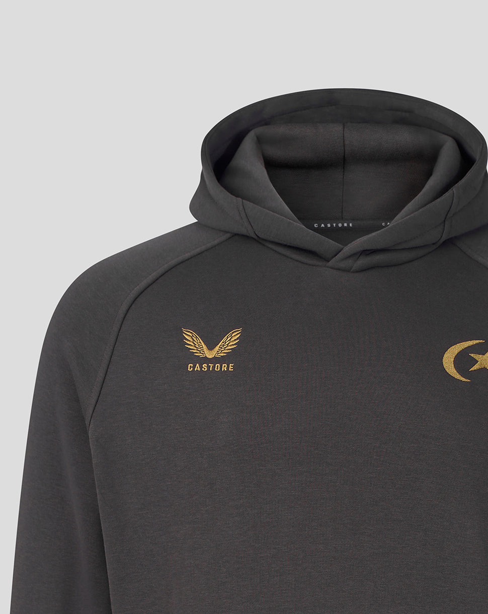 A close-up of a dark gray hooded sweatshirt featuring gold embroidered logos on the chest, including a winged emblem with the word 'CASTORE' on the left chest and a crescent and star emblem on the right chest, set against a light gray background.