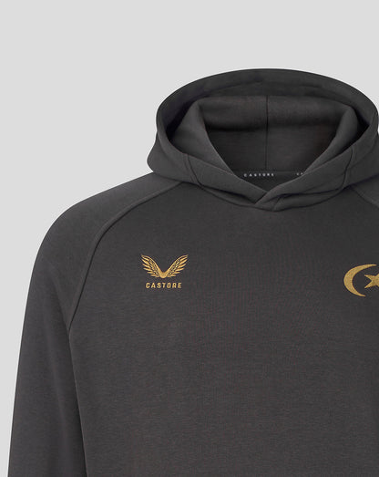 A close-up of a dark gray hooded sweatshirt featuring gold embroidered logos on the chest, including a winged emblem with the word 'CASTORE' on the left chest and a crescent and star emblem on the right chest, set against a light gray background.