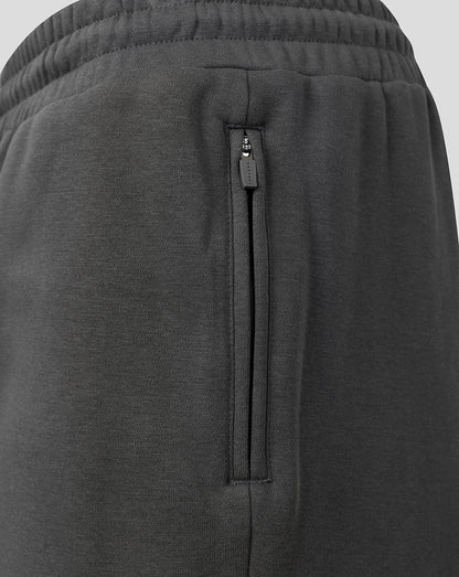 Close-up of dark gray heathered fabric with a vertical zippered pocket and an elastic waistband.