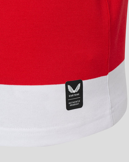Close-up of a red and white color-blocked knit garment, showing a black Castore brand patch on the white hem.