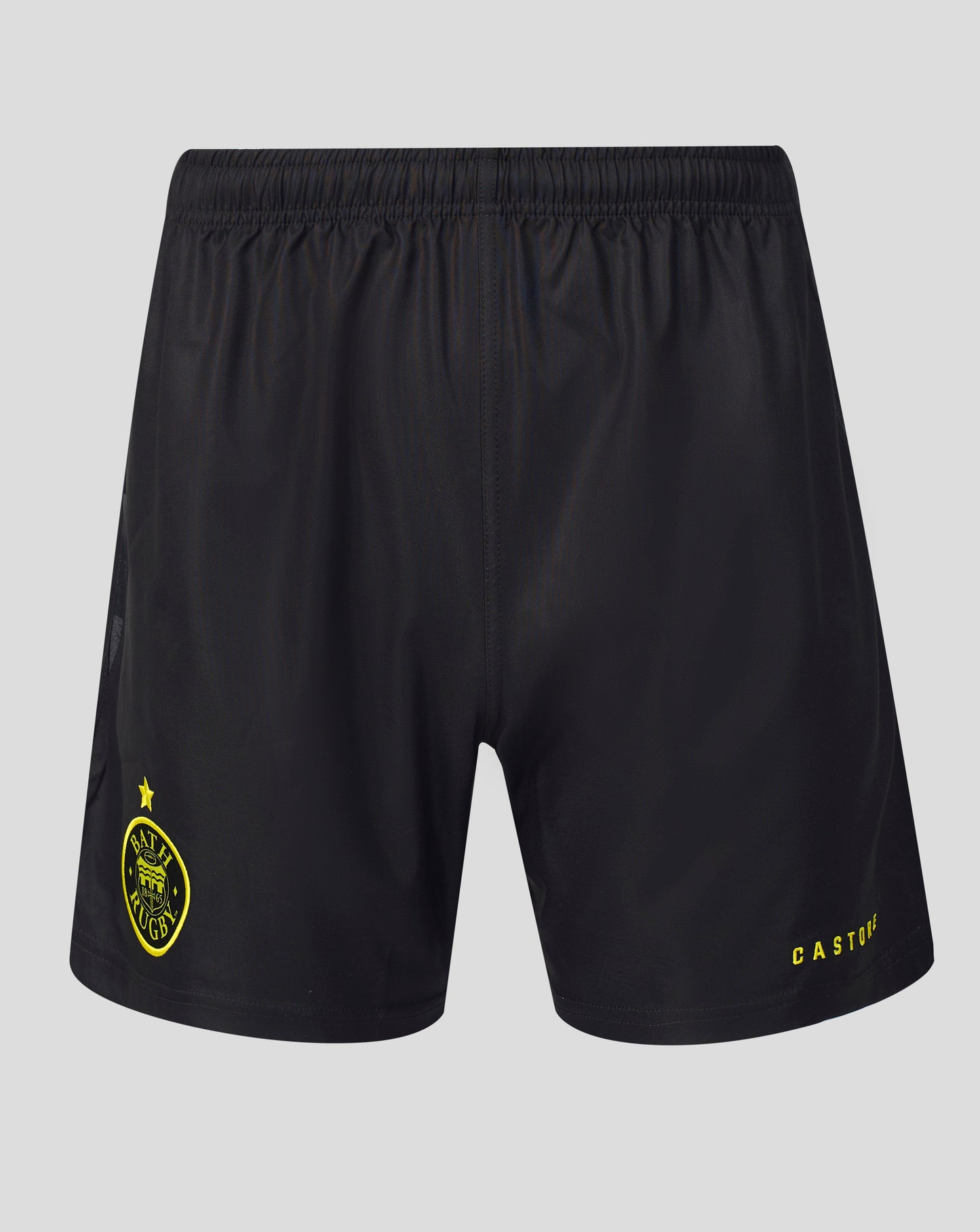 Black athletic shorts with a yellow Castore logo on the left leg and a yellow crest with a star on the right leg, shown against a light gray background.