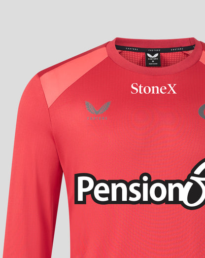 A close-up of a red long-sleeve athletic jersey with 'StoneX' printed in white on the chest and a large 'Pension' sponsor logo across the front. The brand Castore logo is visible on the left chest.