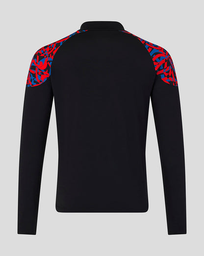 A black long-sleeve athletic top shown from the back, featuring a red and blue abstract patterned shoulder yoke, on a light gray background.
