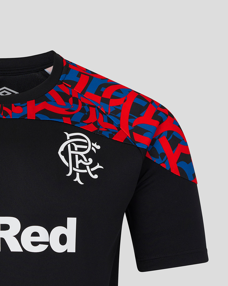 Close-up of a black short-sleeve soccer jersey with a red and blue geometric pattern across the shoulders and upper chest, a white Rangers FC crest on the chest, and part of a white sponsor logo on the lower left. Umbro logo is visible inside the collar.