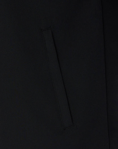 Close-up detail of a black fabric garment showing a vertical welt pocket and smooth matte texture.