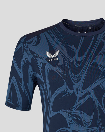 A close-up of a Castore athletic short-sleeve top in navy blue with a lighter blue marbled pattern and a white wing logo on the chest, set against a light gray background.