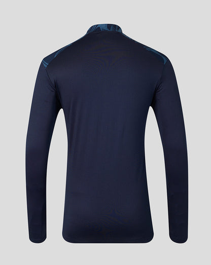 A dark navy long-sleeve athletic top shown from the back, featuring subtle tonal wave patterns and a subtle blue patterned collar and shoulder details, set against a solid light gray background.