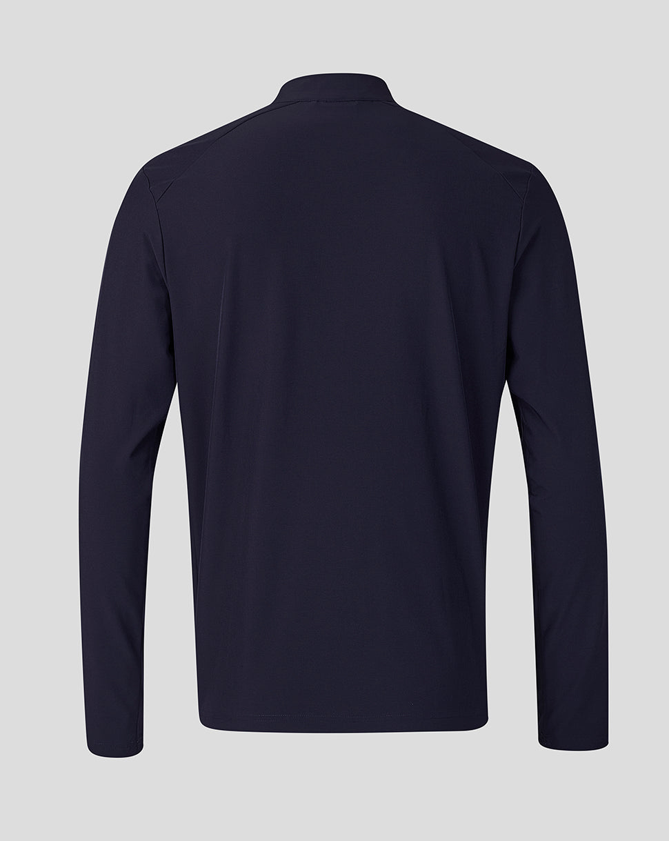 A dark navy long-sleeve athletic top shown from the back, featuring a high collar and a clean, flat silhouette against a solid light gray background.