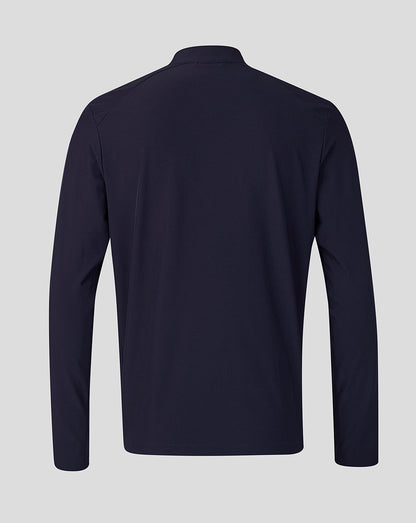 A dark navy long-sleeve athletic top shown from the back, featuring a high collar and a clean, flat silhouette against a solid light gray background.