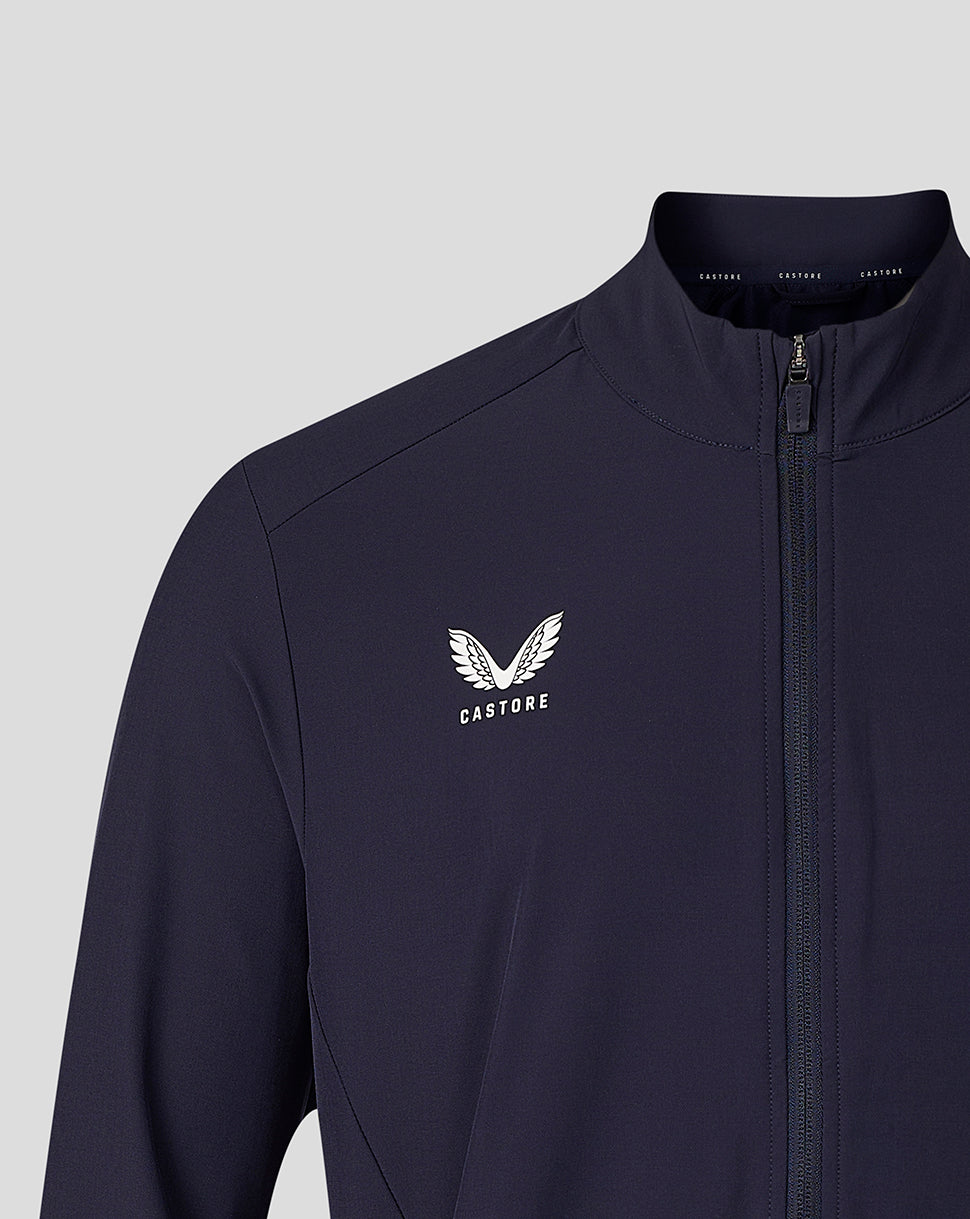 A close-up of a navy blue zip-up jacket with a white Castore wing logo and brand name printed on the left chest, set against a solid light gray background.