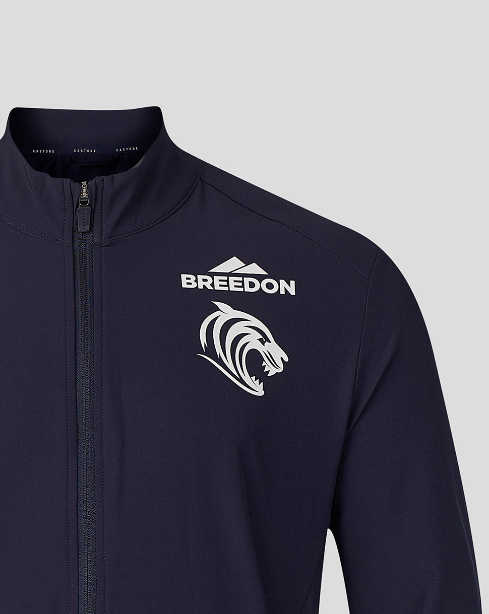 A close-up of a dark navy athletic jacket featuring a white 'BREEDON' text logo and a white stylized lion head graphic on the left chest, set against a solid light gray background.