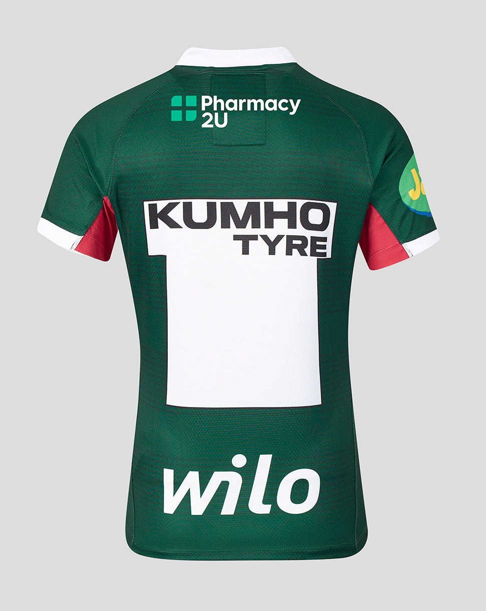 Back view of a dark green short-sleeve sports jersey with white and red accents, featuring sponsor logos including Pharmacy 2U, Kumho Tyre, and wilO on a light gray background.
