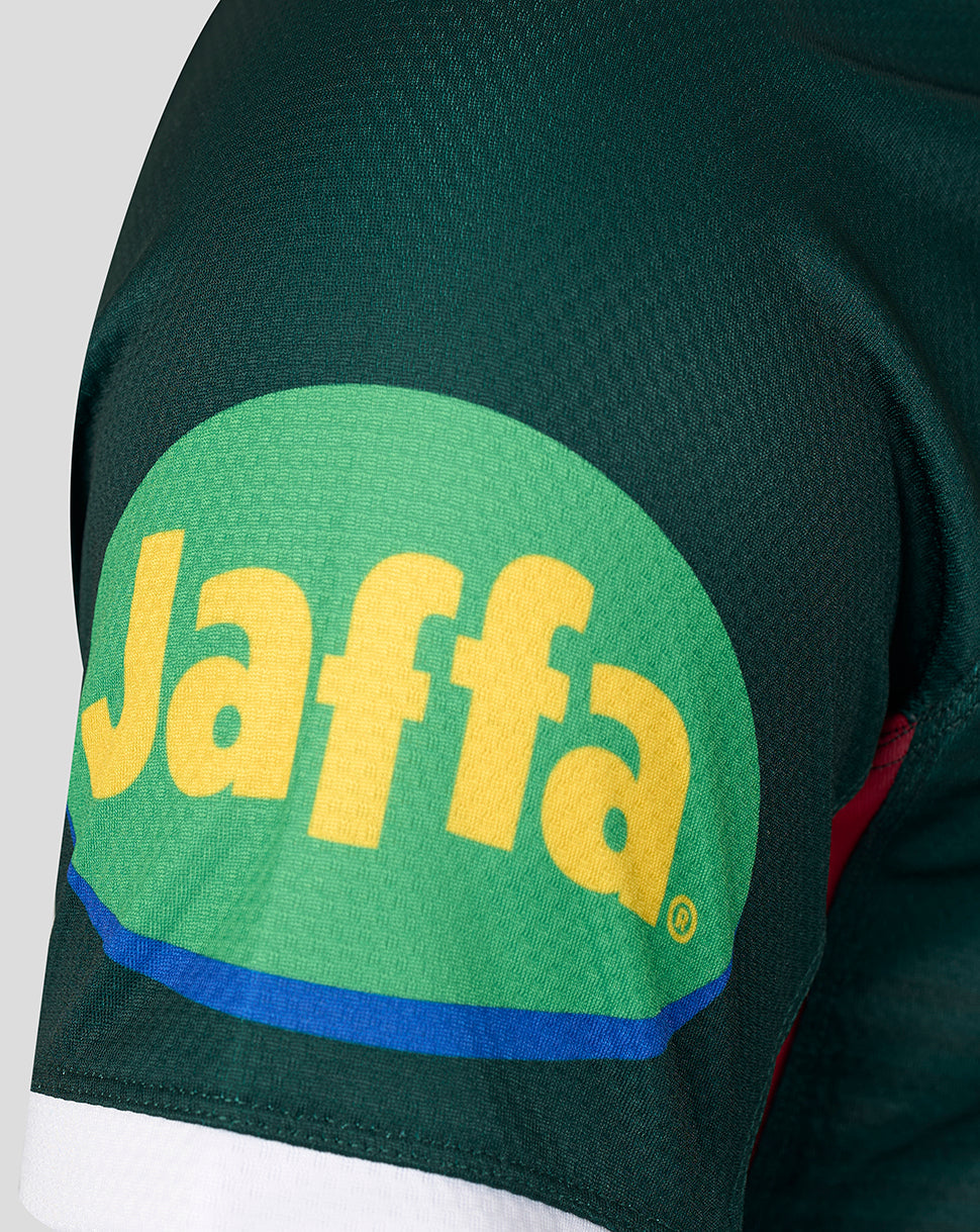 Close-up of a dark green athletic jersey sleeve featuring a large green oval patch with the yellow Jaffa logo and a blue stripe.