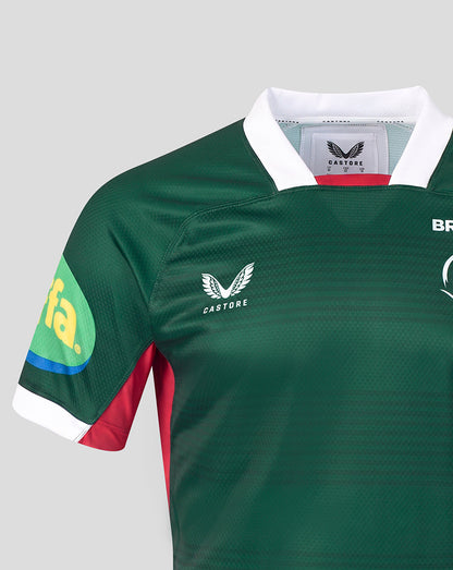 Close-up of a dark green Castore rugby jersey with a white collar, red and white sleeve accents, and a green sponsor logo on the right sleeve, shown against a light gray background.