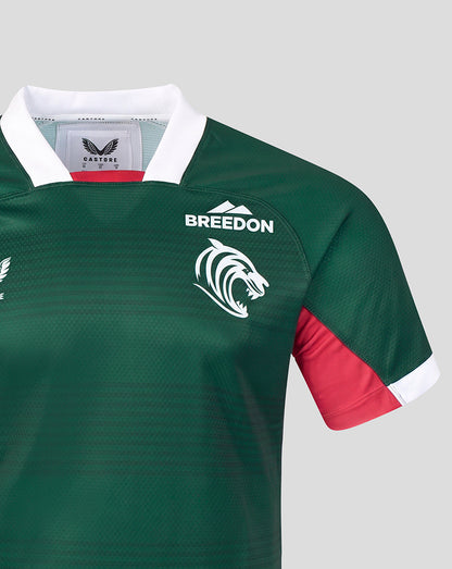 Close-up of a green rugby jersey with a white collar, white 'BREEDON' text and lion logo on the chest, and a red sleeve panel with a white cuff.