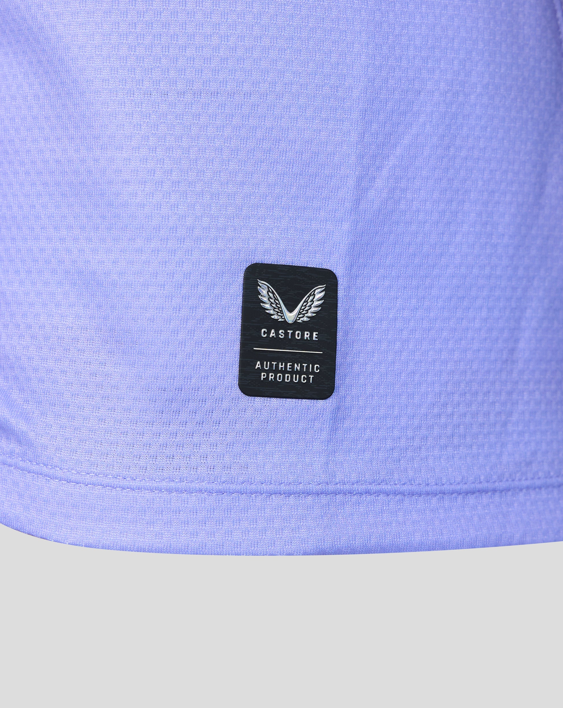 Close-up of a light periwinkle blue athletic jersey with a black Castore Authentic Product patch on the front.