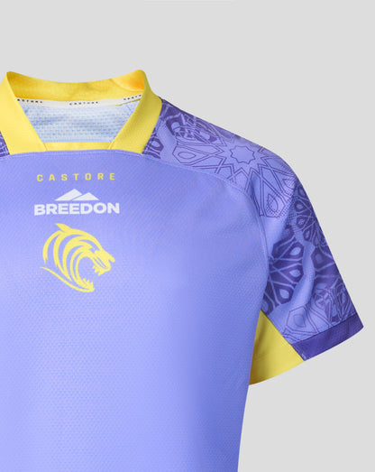 A close-up of a short-sleeve athletic jersey in light purple with yellow trim, patterned sleeves, and the words 'BREEDON' and a yellow lion logo on the chest, shown against a light gray background.