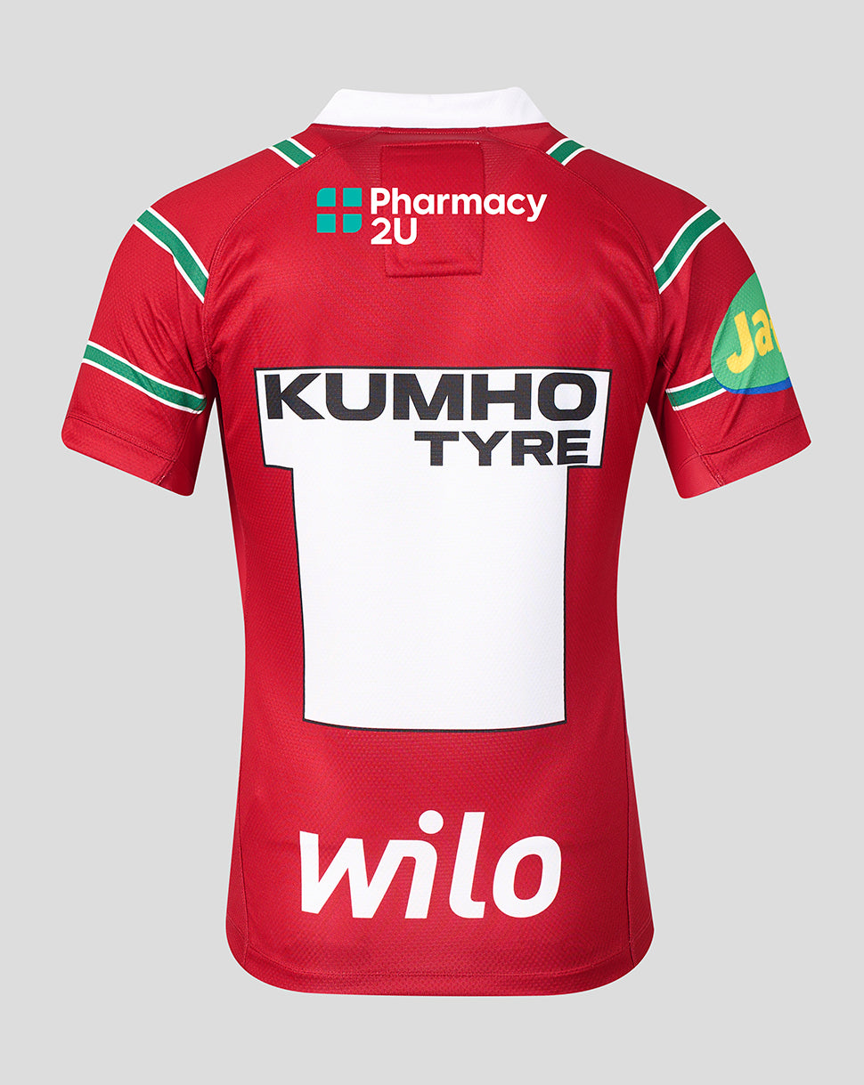 The back of a red short-sleeve rugby jersey with green and white shoulder stripes, featuring large white sponsor logos including Pharmacy 2U, Kumho Tyre, Wilo, and a partial Jaeger logo on the sleeve, set against a solid gray background.