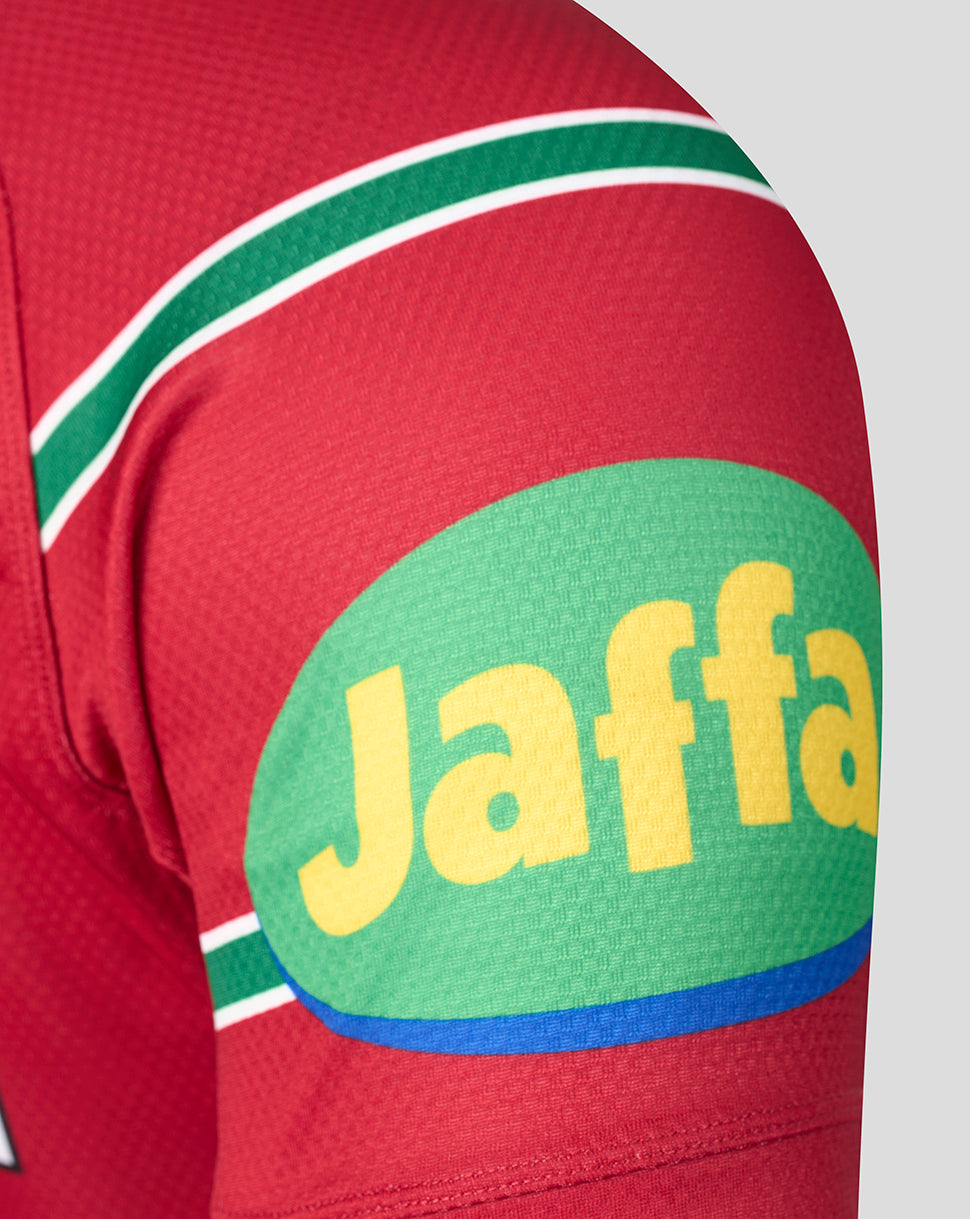 Close-up of a red sports jersey sleeve featuring green and white stripes and a large green oval sponsor logo with yellow 'Jaffa' lettering.