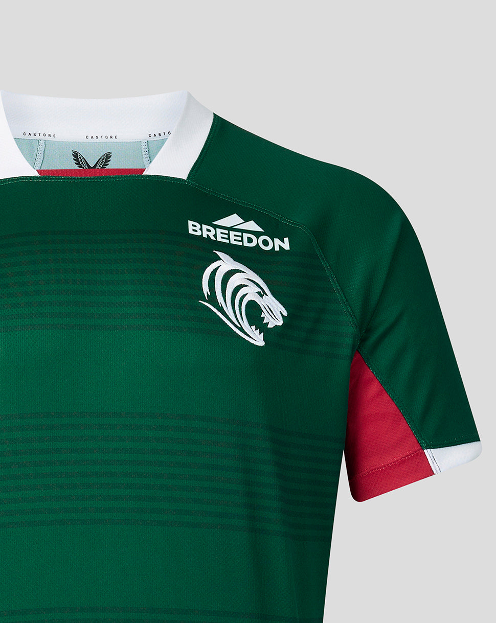 Close-up of a green rugby jersey with a white collar, red sleeve panel, white 'BREEDON' text, and a white lion logo on a light gray background.