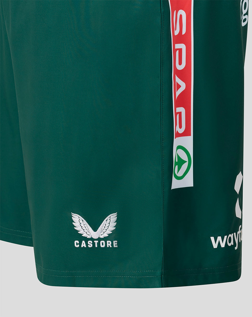 Close-up of dark green athletic shorts showing the Castore wing logo in white on the lower left leg, a vertical red and white sponsor stripe on the right leg, and partial Wayfarer branding near the hem.