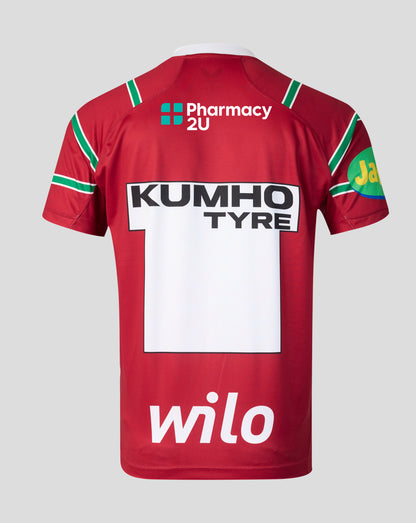 The back of a red short-sleeve sports jersey with green and white trim, featuring 'KUMHO TYRE' and 'Pharmacy 2U' sponsor logos, on a light gray background.