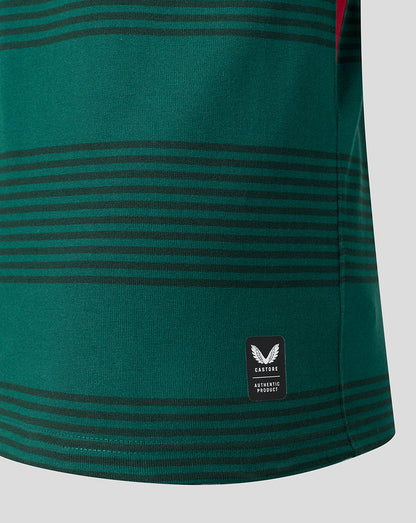 Close-up of a green athletic jersey with horizontal dark stripes and a small black Castore Authentic patch near the hem.