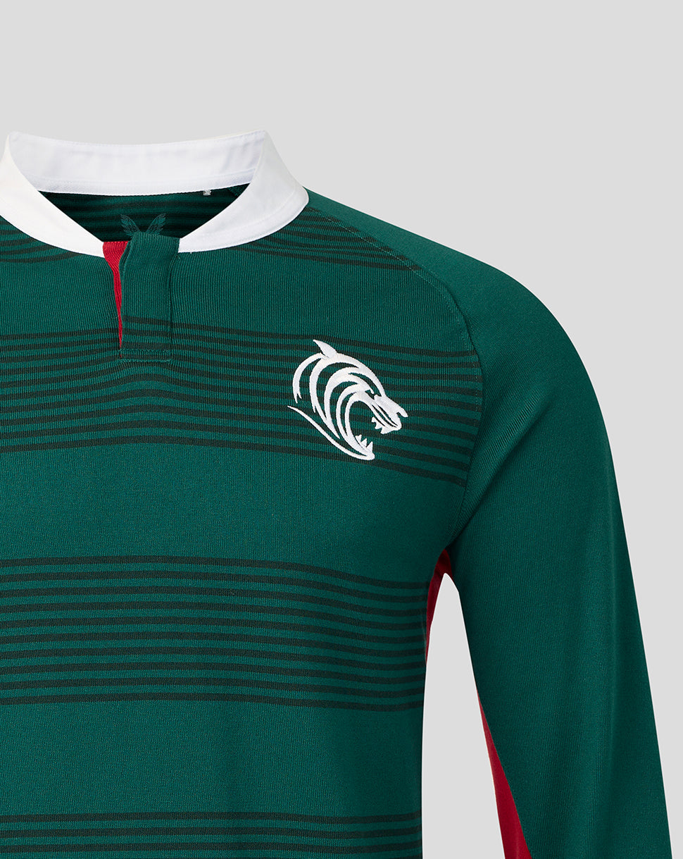 Close-up of a dark green long-sleeve rugby jersey with thin horizontal dark stripes, a white collar, a partial white zipper placket, and a white wolf head logo on the left chest.