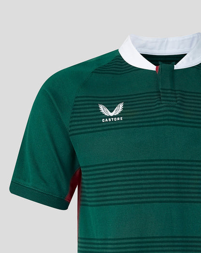 Close-up of a green short-sleeve rugby jersey with horizontal dark green stripes, a white collar, and a white Castore wing logo on the chest.